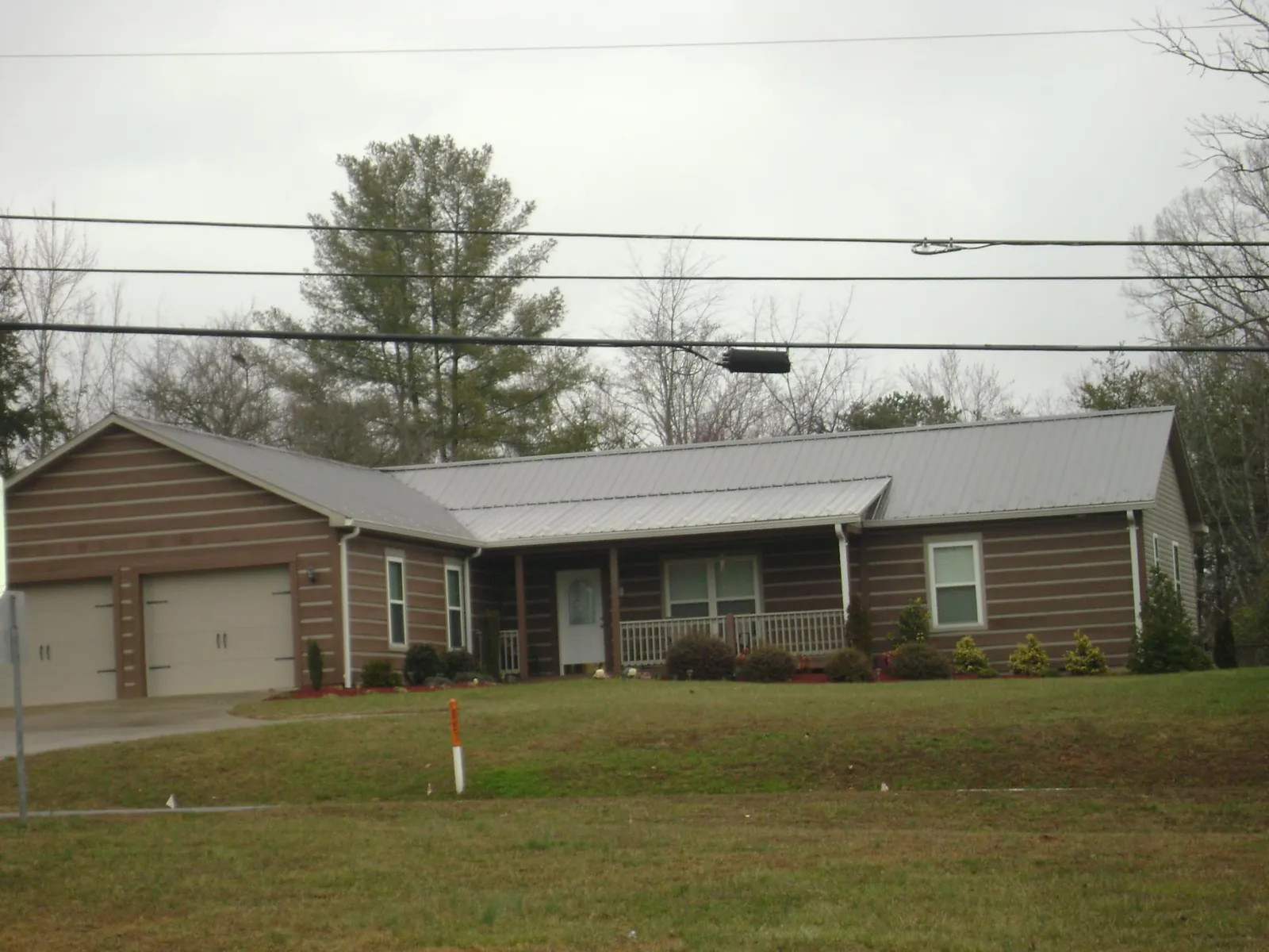 Gray metal roof on a log sided ranch home with a front porch in Cambridge